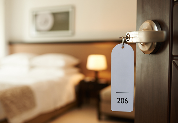 A hotel room with a neatly made bed and a closed door